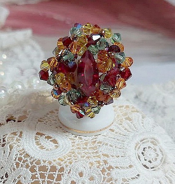 Bague Iroise mont&eacute;e avec des toupies et une navette en Cristal aux couleurs Rouge, Jaune, Topaz et Vert entrelac&eacute;es avec des rocailles Bronze sur des facettes en verre de boh&egrave;me Rouge