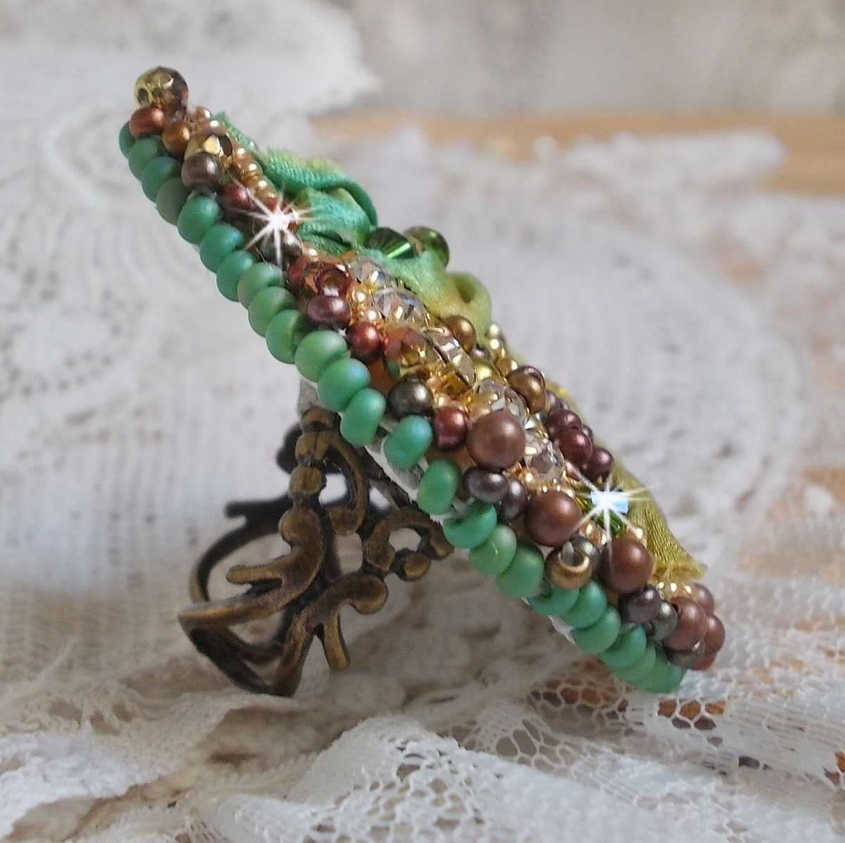 Bague Lune V&eacute;nitienne brod&eacute;e avec un ruban de soie Orange, Vert et Jaune, cristaux : toupies, perles rondes nacr&eacute;es et chatons. S&rsquo;ajoute des facettes et rocailles en Verre sur une bague filigran&eacute;e 