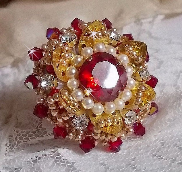 Bague L&rsquo;Oiseau des Iles Rouge Dor&eacute; avec un cabochon Rouge sur une estampe dor&eacute;e orn&eacute;e de cristaux : toupies et chatons. Les perles rondes nacr&eacute;es Ivoire et Rouge compl&egrave;tent cette bague r&eacute;glable Dor&eacute;e