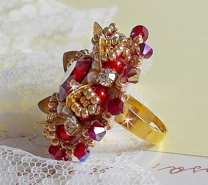 Bague L&rsquo;Oiseau des Iles Rouge Dor&eacute; avec un cabochon Rouge sur une estampe dor&eacute;e orn&eacute;e de cristaux : toupies et chatons. Les perles rondes nacr&eacute;es Ivoire et Rouge compl&egrave;tent cette bague r&eacute;glable Dor&eacute;e