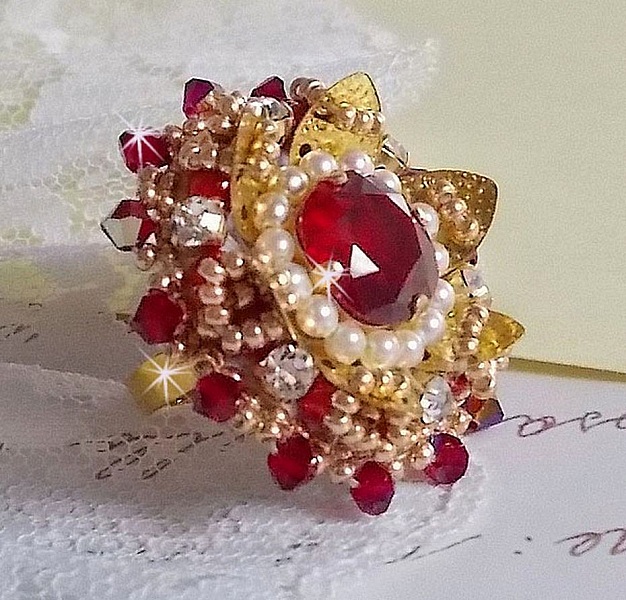 Bague L&rsquo;Oiseau des Iles Rouge Dor&eacute; avec un cabochon Rouge sur une estampe dor&eacute;e orn&eacute;e de cristaux : toupies et chatons. Les perles rondes nacr&eacute;es Ivoire et Rouge compl&egrave;tent cette bague r&eacute;glable Dor&eacute;e