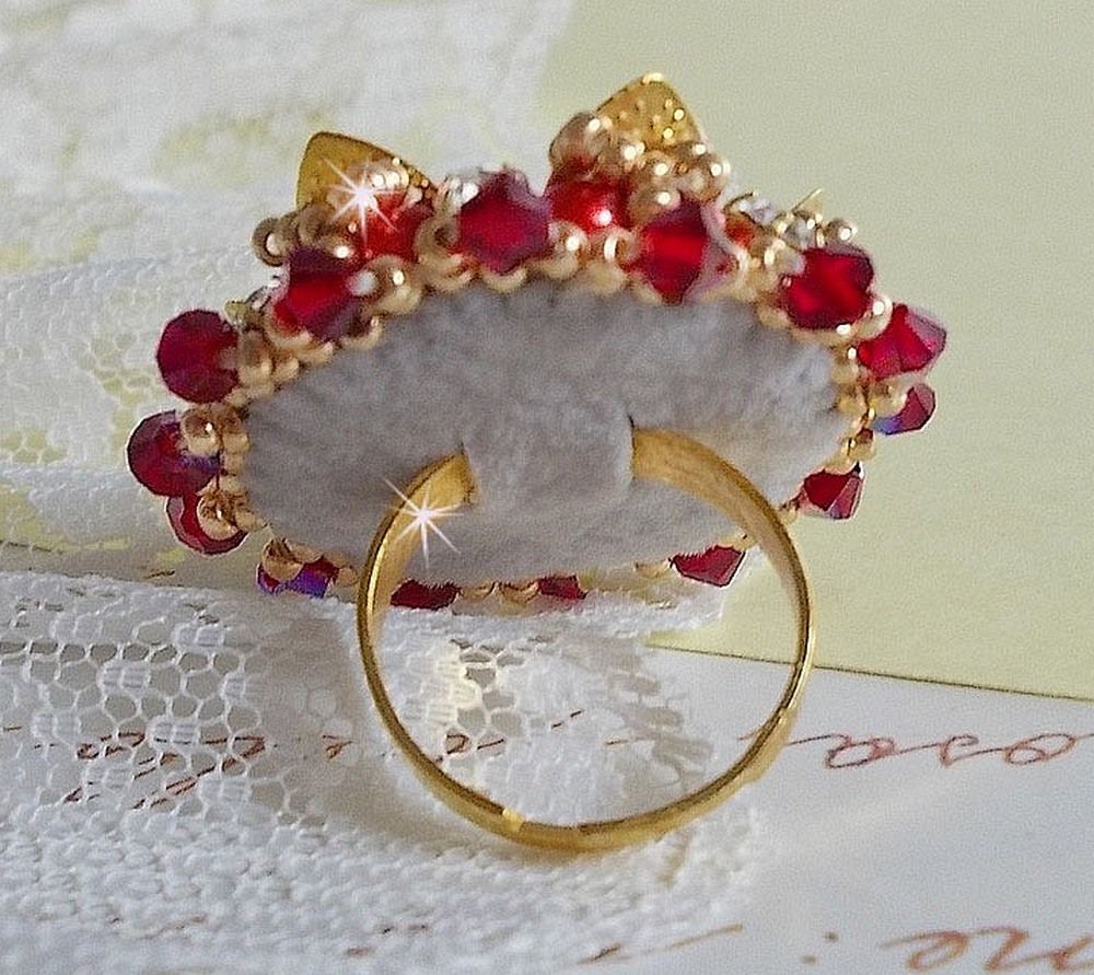 Bague L&rsquo;Oiseau des Iles Rouge Dor&eacute; avec un cabochon Rouge sur une estampe dor&eacute;e orn&eacute;e de cristaux : toupies et chatons. Les perles rondes nacr&eacute;es Ivoire et Rouge compl&egrave;tent cette bague r&eacute;glable Dor&eacute;e