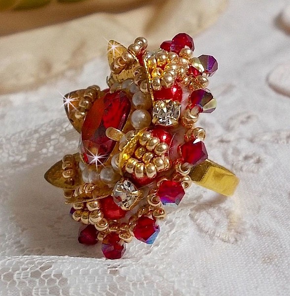 Bague L&rsquo;Oiseau des Iles Rouge Dor&eacute; avec un cabochon Rouge sur une estampe dor&eacute;e orn&eacute;e de cristaux : toupies et chatons. Les perles rondes nacr&eacute;es Ivoire et Rouge compl&egrave;tent cette bague r&eacute;glable Dor&eacute;e