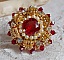 Bague L&rsquo;Oiseau des Iles Rouge Dor&eacute; avec un cabochon Rouge sur une estampe dor&eacute;e orn&eacute;e de cristaux : toupies et chatons. Les perles rondes nacr&eacute;es Ivoire et Rouge compl&egrave;tent cette bague r&eacute;glable Dor&eacute;e