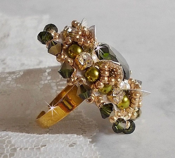 Bague L&rsquo;Oiseau des Iles Vert Argent avec un cabochon Vert sur une estampe Argent&eacute;e orn&eacute;e de cristaux : toupies et chatons. Les perles rondes nacr&eacute;es Ivoire et Olivine compl&egrave;te cette bague r&eacute;glable. 