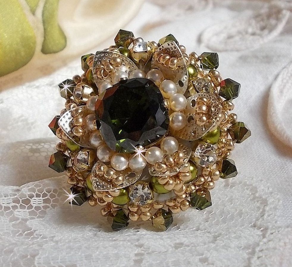 Bague L&rsquo;Oiseau des Iles Vert Argent avec un cabochon Vert sur une estampe Argent&eacute;e orn&eacute;e de cristaux : toupies et chatons. Les perles rondes nacr&eacute;es Ivoire et Olivine compl&egrave;te cette bague r&eacute;glable. 