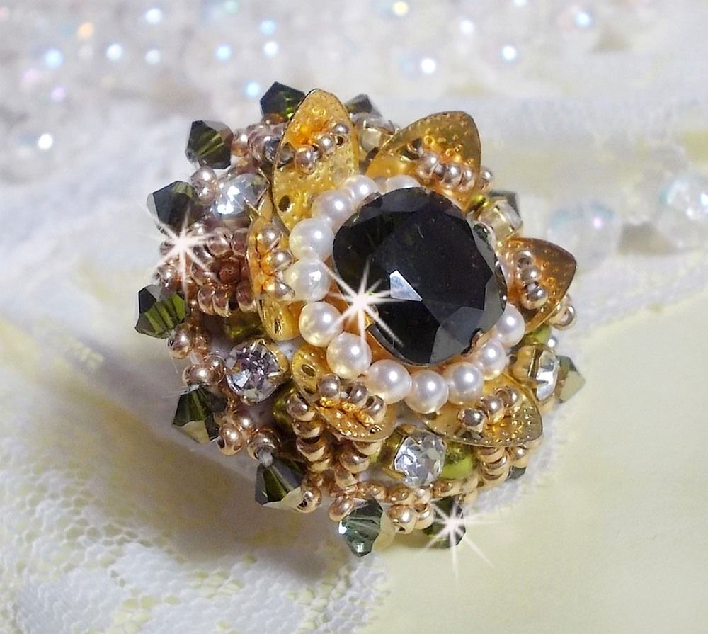 Bague L&rsquo;Oiseau des Iles Vert Dor&eacute;e avec un cabochon Vert sur une estampe dor&eacute;e orn&eacute;e de cristaux : toupies et chatons. Les perles rondes nacr&eacute;es Ivoire et Olivine compl&egrave;te cette bague r&eacute;glable. 