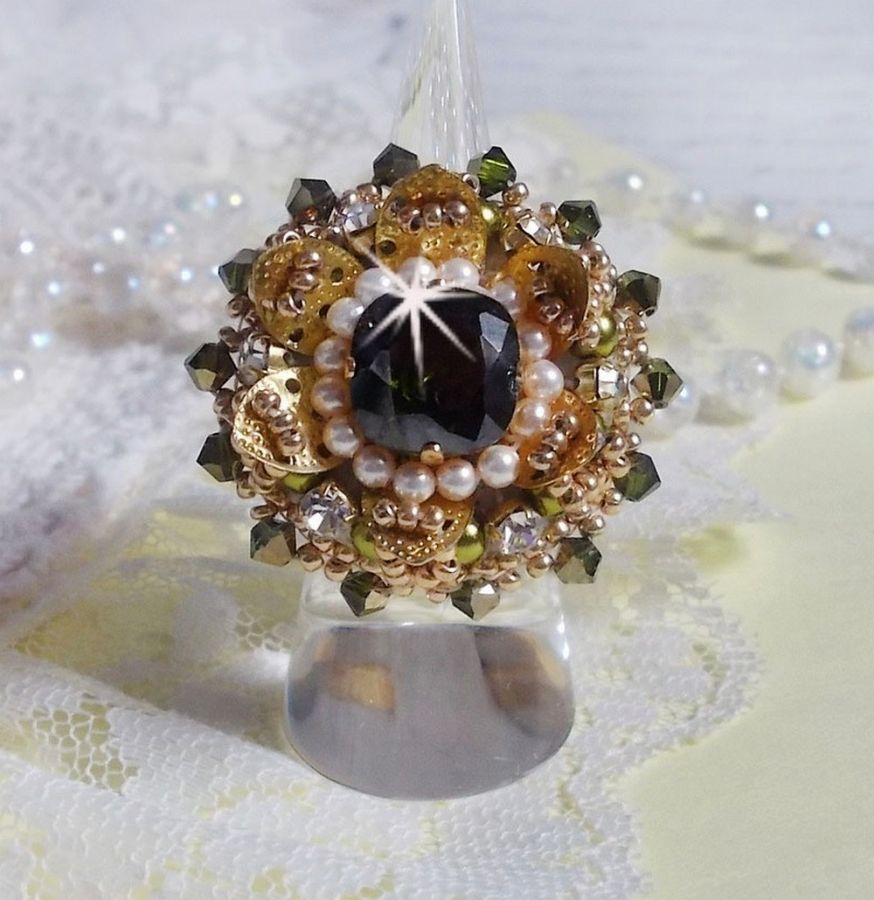Bague L&rsquo;Oiseau des Iles Vert Dor&eacute;e avec un cabochon Vert sur une estampe dor&eacute;e orn&eacute;e de cristaux : toupies et chatons. Les perles rondes nacr&eacute;es Ivoire et Olivine compl&egrave;te cette bague r&eacute;glable. 