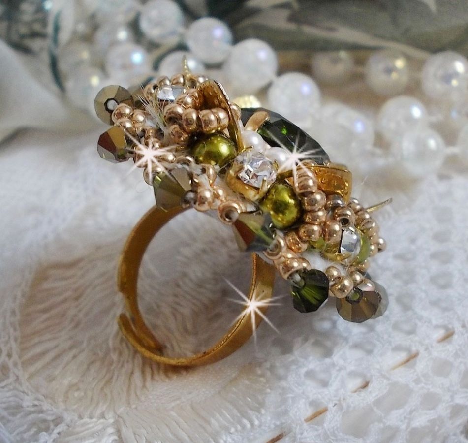 Bague L&rsquo;Oiseau des Iles Vert Dor&eacute;e avec un cabochon Vert sur une estampe dor&eacute;e orn&eacute;e de cristaux : toupies et chatons. Les perles rondes nacr&eacute;es Ivoire et Olivine compl&egrave;te cette bague r&eacute;glable. 