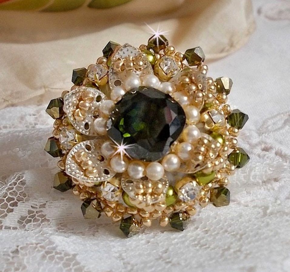 Bague L&rsquo;Oiseau des Iles Vert Argent avec un cabochon Vert sur une estampe Argent&eacute;e orn&eacute;e de cristaux : toupies et chatons. Les perles rondes nacr&eacute;es Ivoire et Olivine compl&egrave;te cette bague r&eacute;glable. 