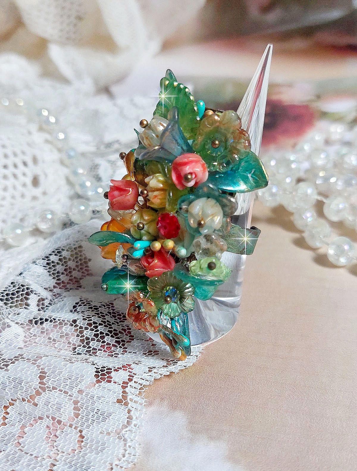 Bague Patiflo d&rsquo;une composition florale cr&eacute;&eacute;e avec des cristaux, fleurs en R&eacute;sine, perles, clochettes, pens&eacute;es, boutons de rose en Verre, estampes et coupelles. Le tout est mont&eacute; sur une bague estampe