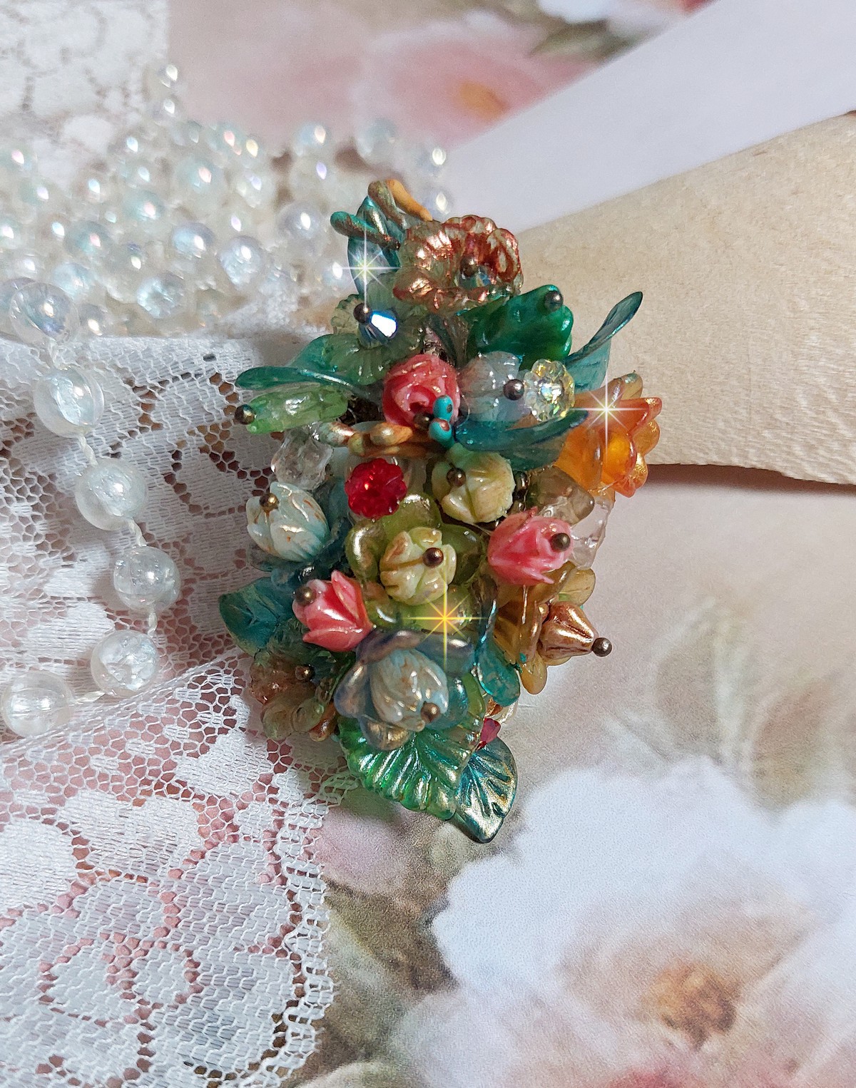 Bague Patiflo d&rsquo;une composition florale cr&eacute;&eacute;e avec des cristaux, fleurs en R&eacute;sine, perles, clochettes, pens&eacute;es, boutons de rose en Verre, estampes et coupelles. Le tout est mont&eacute; sur une bague estampe