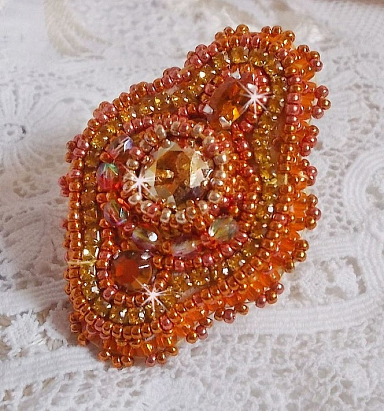 Bague Rumba brod&eacute;e avec un cabochon en Cristal de Swarovski Sunshine orn&eacute;e de facettes Cristal Jaune/Orange et Abricot &agrave; laquelle s'ajoute des chatons, rocailles Oranges et Dor&eacute;es sur bague Dor&eacute;e