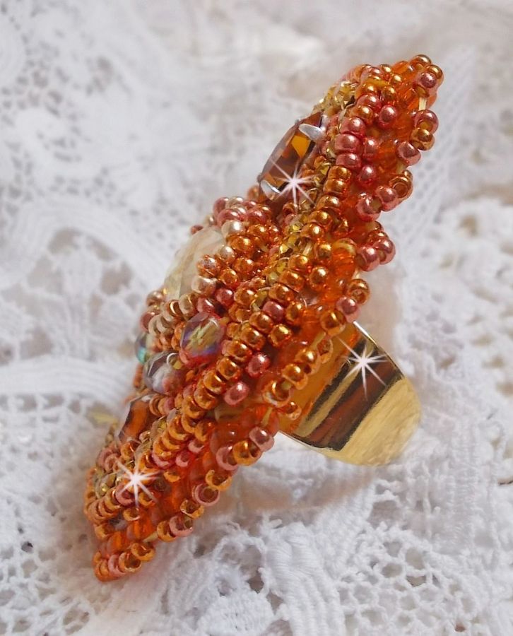 Bague Rumba brod&eacute;e avec un cabochon en Cristal de Swarovski Sunshine orn&eacute;e de facettes Cristal Jaune/Orange et Abricot &agrave; laquelle s'ajoute des chatons, rocailles Oranges et Dor&eacute;es sur bague Dor&eacute;e