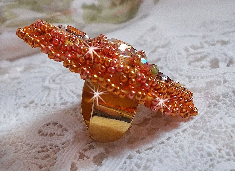 Bague Rumba brod&eacute;e avec un cabochon en Cristal de Swarovski Sunshine orn&eacute;e de facettes Cristal Jaune/Orange et Abricot &agrave; laquelle s'ajoute des chatons, rocailles Oranges et Dor&eacute;es sur bague Dor&eacute;e
