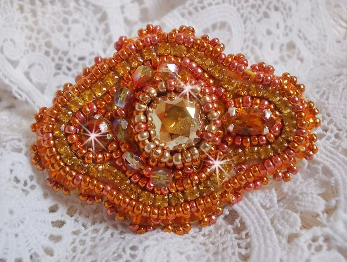 Bague Rumba brod&eacute;e avec un cabochon en Cristal de Swarovski Sunshine orn&eacute;e de facettes Cristal Jaune/Orange et Abricot &agrave; laquelle s'ajoute des chatons, rocailles Oranges et Dor&eacute;es sur bague Dor&eacute;e