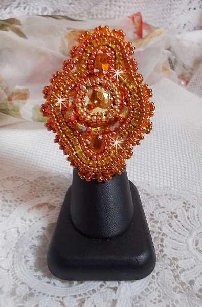 Bague Rumba brod&eacute;e avec un cabochon en Cristal de Swarovski Sunshine orn&eacute;e de facettes Cristal Jaune/Orange et Abricot &agrave; laquelle s'ajoute des chatons, rocailles Oranges et Dor&eacute;es sur bague Dor&eacute;e