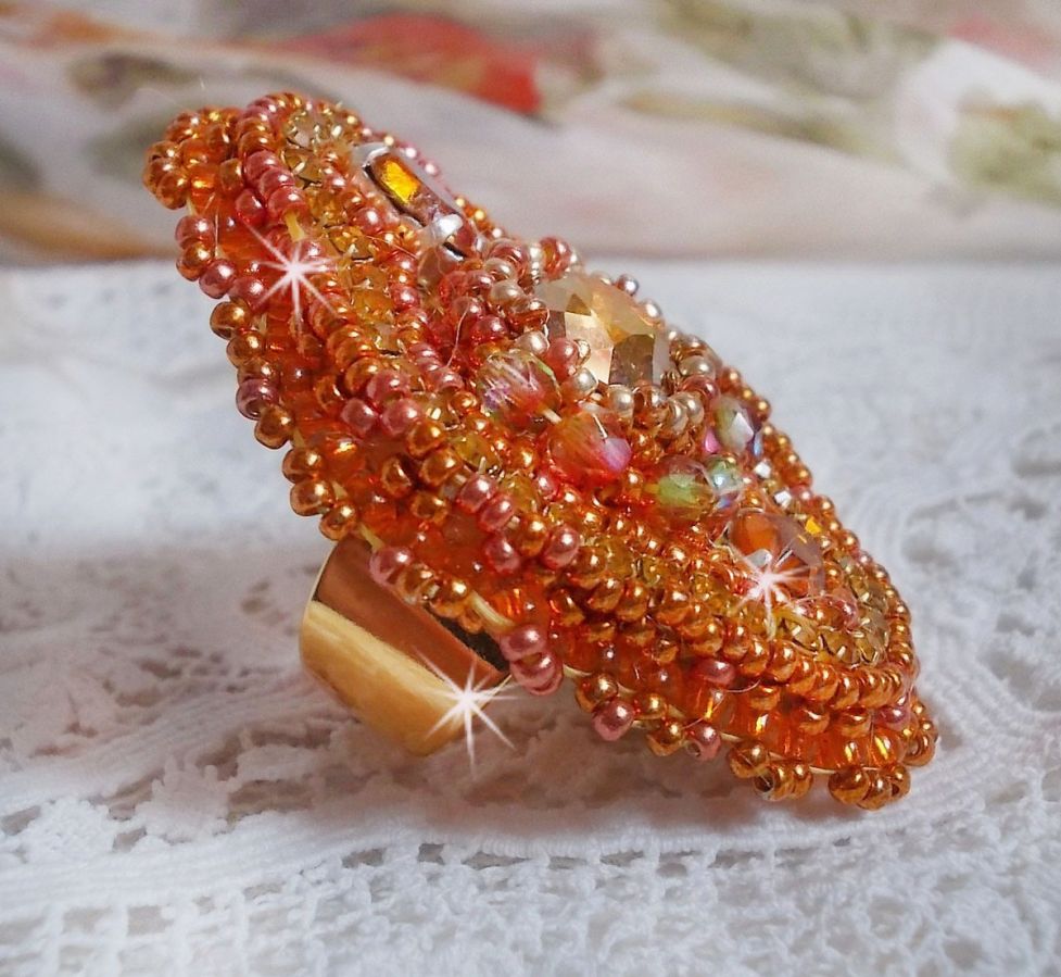 Bague Rumba brod&eacute;e avec un cabochon en Cristal de Swarovski Sunshine orn&eacute;e de facettes Cristal Jaune/Orange et Abricot &agrave; laquelle s'ajoute des chatons, rocailles Oranges et Dor&eacute;es sur bague Dor&eacute;e