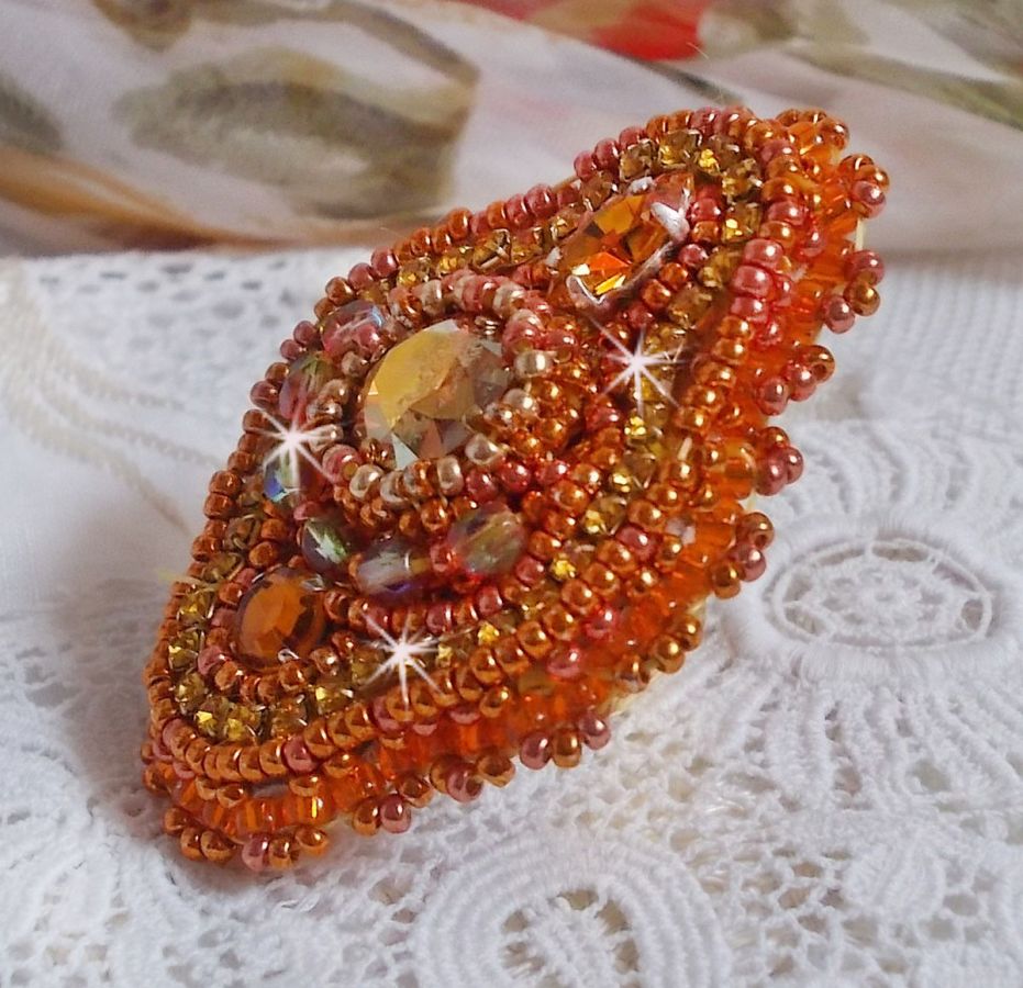 Bague Rumba brod&eacute;e avec un cabochon en Cristal de Swarovski Sunshine orn&eacute;e de facettes Cristal Jaune/Orange et Abricot &agrave; laquelle s'ajoute des chatons, rocailles Oranges et Dor&eacute;es sur bague Dor&eacute;e