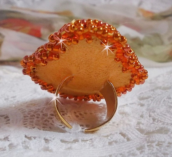 Bague Rumba brod&eacute;e avec un cabochon en Cristal de Swarovski Sunshine orn&eacute;e de facettes Cristal Jaune/Orange et Abricot &agrave; laquelle s'ajoute des chatons, rocailles Oranges et Dor&eacute;es sur bague Dor&eacute;e
