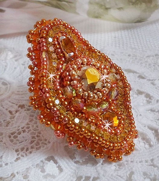 Bague Rumba brod&eacute;e avec un cabochon en Cristal de Swarovski Sunshine orn&eacute;e de facettes Cristal Jaune/Orange et Abricot &agrave; laquelle s'ajoute des chatons, rocailles Oranges et Dor&eacute;es sur bague Dor&eacute;e