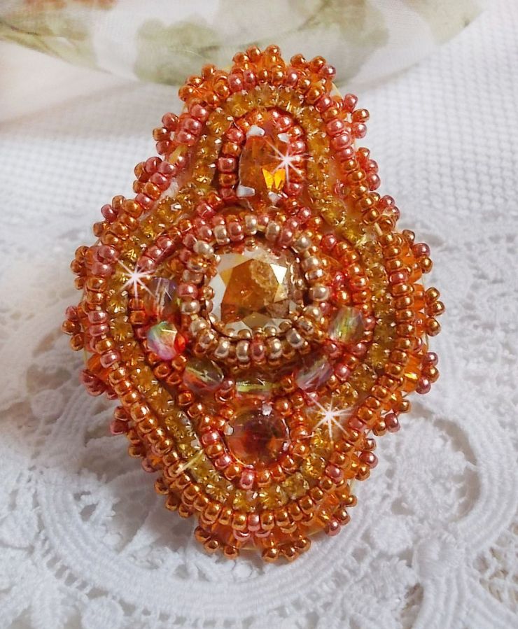 Bague Rumba brod&eacute;e avec un cabochon en Cristal de Swarovski Sunshine orn&eacute;e de facettes Cristal Jaune/Orange et Abricot &agrave; laquelle s'ajoute des chatons, rocailles Oranges et Dor&eacute;es sur bague Dor&eacute;e