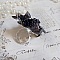 Bague Soir de Lune cr&eacute;&eacute;e avec des fleurs lucites Noires et Grises peintes &agrave; la main, cristaux, perles en r&eacute;sine, perles en verre et coupelle argent&eacute;e. Le tout est mont&eacute; sur une bague argent&eacute;e