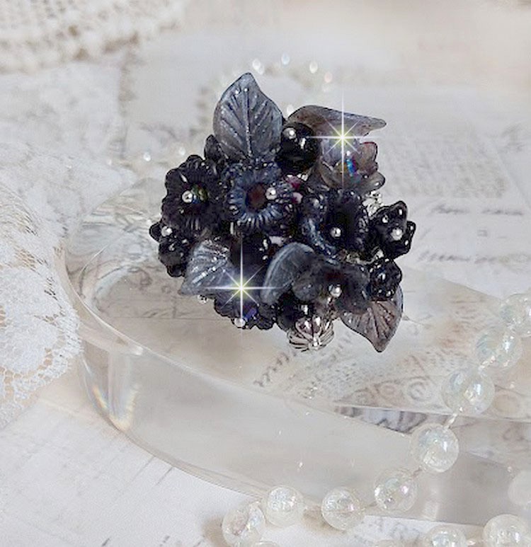 Bague Soir de Lune cr&eacute;&eacute;e avec des fleurs lucites Noires et Grises peintes &agrave; la main, cristaux, perles en r&eacute;sine, perles en verre et coupelle argent&eacute;e. Le tout est mont&eacute; sur une bague argent&eacute;e