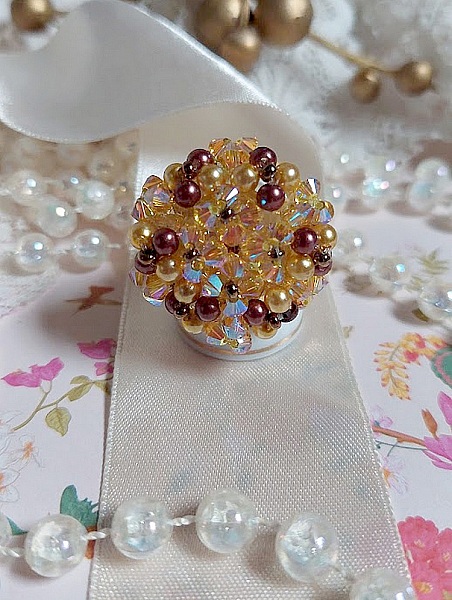 Bague Soleil mont&eacute;e avec des toupies en Cristal de Swarovski aux couleurs Topaze, Gold et Marron &agrave; laquelle s&rsquo;ajoute des facettes en Verre de Boh&egrave;me. Les perles s&rsquo;entrelacent avec les rocailles Dor&eacute;es