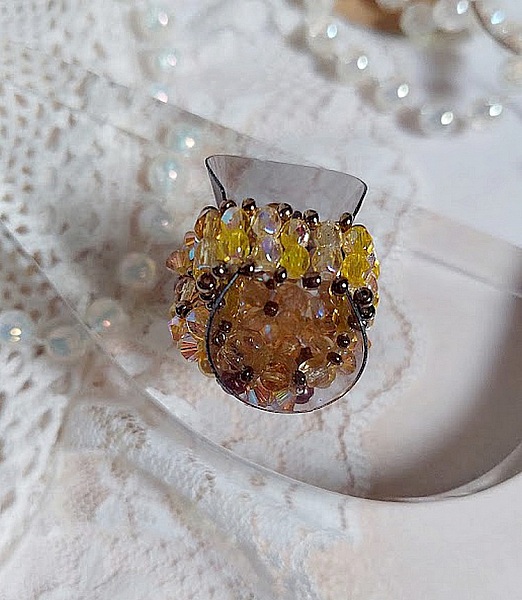 Bague Soleil mont&eacute;e avec des toupies en Cristal de Swarovski aux couleurs Topaze, Gold et Marron &agrave; laquelle s&rsquo;ajoute des facettes en Verre de Boh&egrave;me. Les perles s&rsquo;entrelacent avec les rocailles Dor&eacute;es