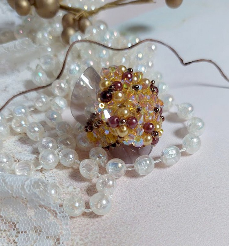 Bague Soleil mont&eacute;e avec des toupies en Cristal de Swarovski aux couleurs Topaze, Gold et Marron &agrave; laquelle s&rsquo;ajoute des facettes en Verre de Boh&egrave;me. Les perles s&rsquo;entrelacent avec les rocailles Dor&eacute;es