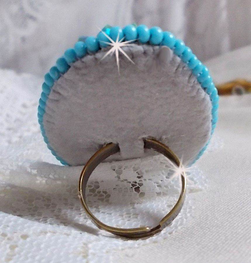 Bague Turquoise au style Am&eacute;rindien avec un cabochon ovale en pierre de gemme : le Turquoise lui-m&ecirc;me orn&eacute; de toupies en Cristal, s&rsquo;ajoute des rocailles en verre Miyuki et tch&egrave;que sur une bague Bronze