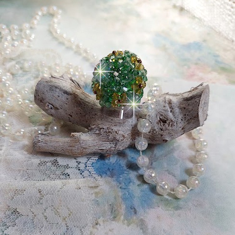 Bague Vert Tendre mont&eacute;e avec des toupies en Cristal dans les nuances de Vert Emerald et Jaune &agrave; laquelle s'ajoute des facettes et des rocailles. Un feuillage verdoyant de fleurs