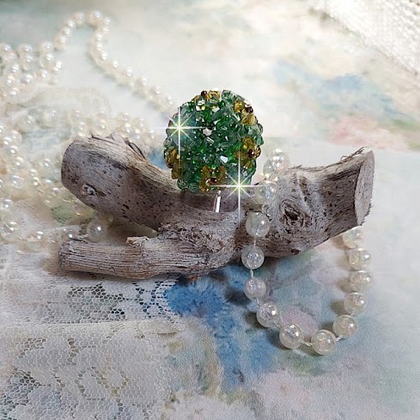 Bague Vert Tendre mont&eacute;e avec des toupies en Cristal dans les nuances de Vert Emerald et Jaune &agrave; laquelle s'ajoute des facettes et des rocailles. Un feuillage verdoyant de fleurs
