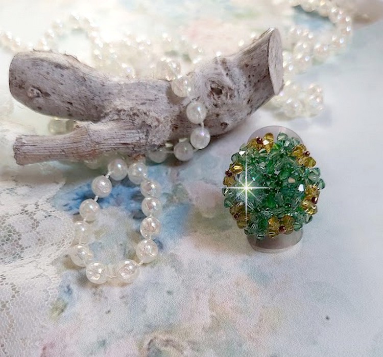 Bague Vert Tendre mont&eacute;e avec des toupies en Cristal dans les nuances de Vert Emerald et Jaune &agrave; laquelle s'ajoute des facettes et des rocailles. Un feuillage verdoyant de fleurs
