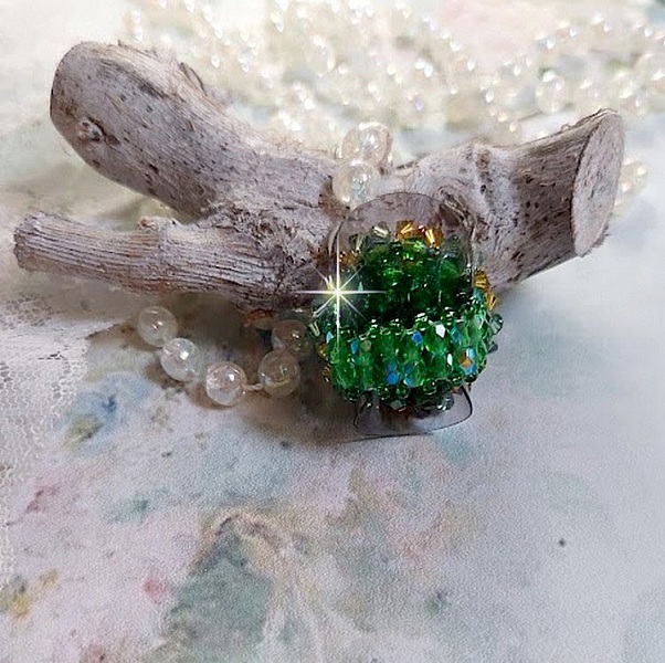 Bague Vert Tendre mont&eacute;e avec des toupies en Cristal dans les nuances de Vert Emerald et Jaune &agrave; laquelle s'ajoute des facettes et des rocailles. Un feuillage verdoyant de fleurs