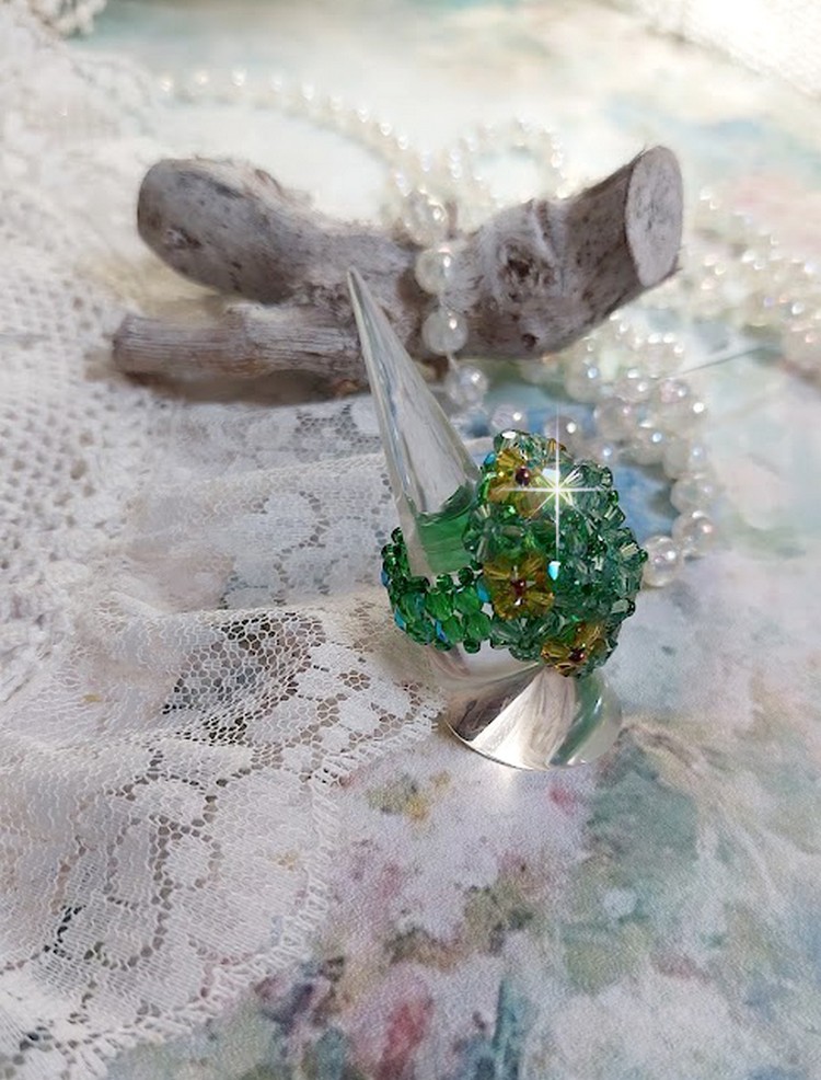 Bague Vert Tendre mont&eacute;e avec des toupies en Cristal dans les nuances de Vert Emerald et Jaune &agrave; laquelle s'ajoute des facettes et des rocailles. Un feuillage verdoyant de fleurs