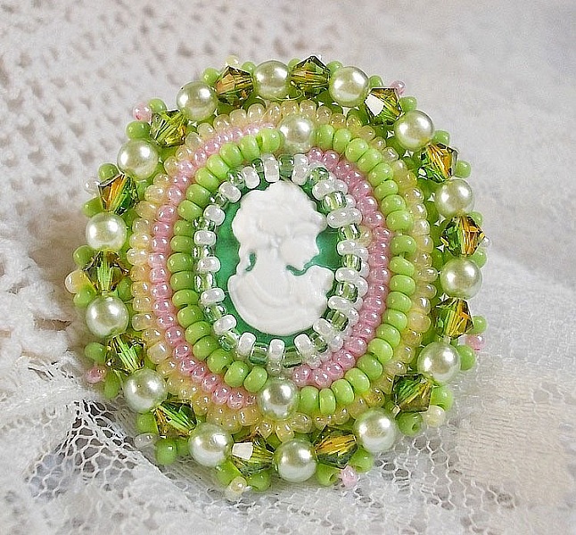 Bague Anisse brod&eacute;e d&rsquo;un cabochon r&eacute;sine repr&eacute;sentant une femme et des roses, orn&eacute;e de rocailles Vert Anis, Rose, Jaune Nacr&eacute; et Ivoire. Elle est finie avec des toupies et perles sur bague r&eacute;glable 