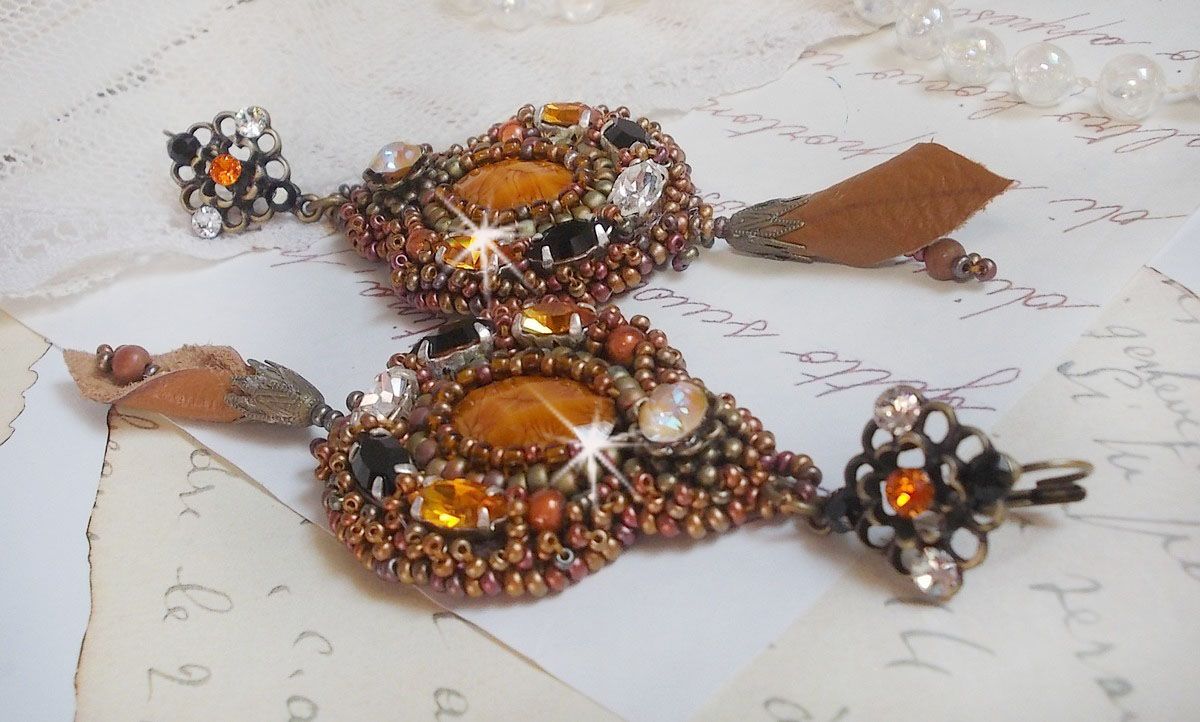 BO Amber Romance avec un cabochon en r&eacute;sine orn&eacute; de cristaux : navettes Topaz, Noir et Cristal avec rocailles. Le cuir compl&egrave;te les pendants avec des perles en Agate sur dormeuses. Un style Am&eacute;rindien
