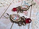 BO Petit Ange avec des cabochons d&rsquo;anges orn&eacute;s d&rsquo;une cha&icirc;ne strass Cristal, breloques, gouttes facett&eacute;es en verre de couleur Siam. Mont&eacute;s sur des pendentifs et des dormeuses en Laiton