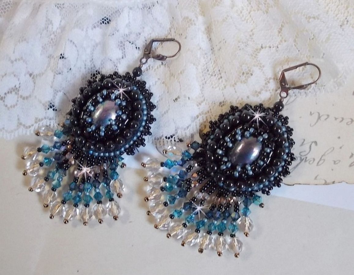 BO Angelot brod&eacute;es avec des cabochons ovales en r&eacute;sine Noire, perles rondes nacr&eacute;es Cristal et toupies. S&rsquo;ajoute des facettes et rocailles. Le tout est mont&eacute; sur des dormeuses Lys en Laiton