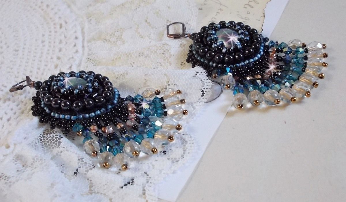 BO Angelot brod&eacute;es avec des cabochons ovales en r&eacute;sine Noire, perles rondes nacr&eacute;es Cristal et toupies. S&rsquo;ajoute des facettes et rocailles. Le tout est mont&eacute; sur des dormeuses Lys en Laiton