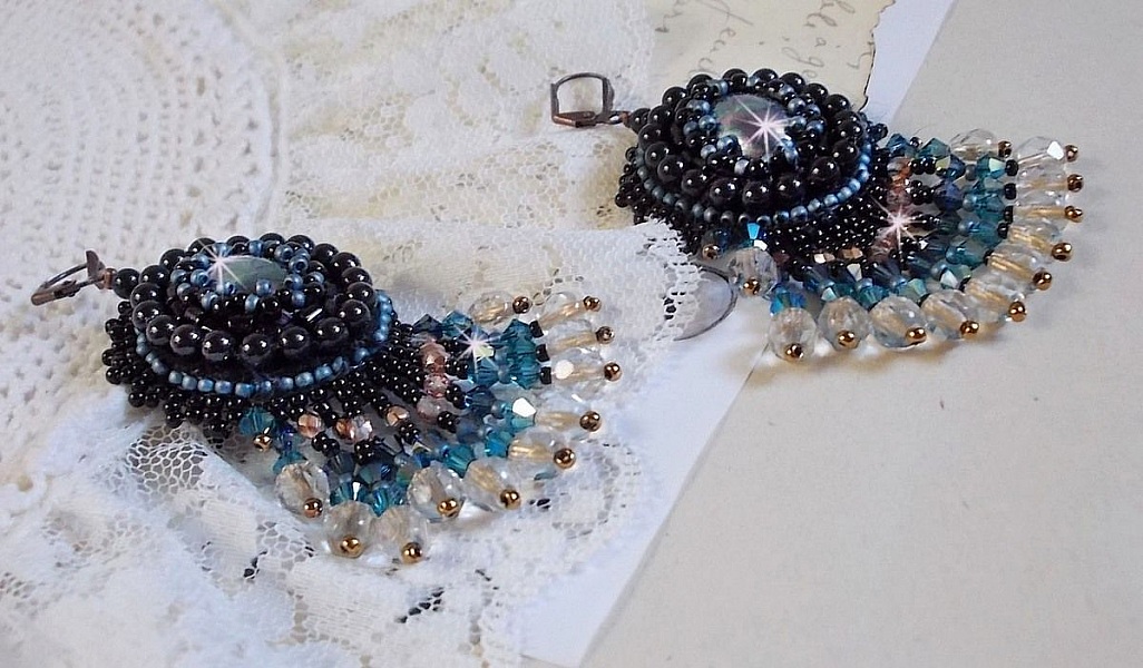 BO Angelot brod&eacute;es avec des cabochons ovales en r&eacute;sine Noire, perles rondes nacr&eacute;es Cristal et toupies. S&rsquo;ajoute des facettes et rocailles. Le tout est mont&eacute; sur des dormeuses Lys en Laiton