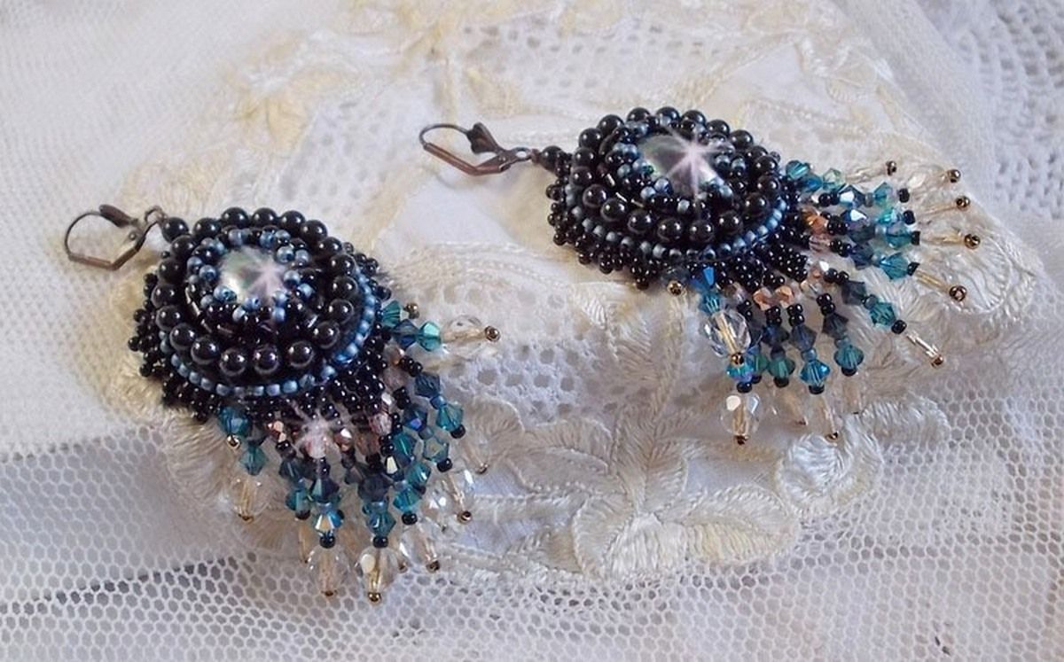 BO Angelot brod&eacute;es avec des cabochons ovales en r&eacute;sine Noire, perles rondes nacr&eacute;es Cristal et toupies. S&rsquo;ajoute des facettes et rocailles. Le tout est mont&eacute; sur des dormeuses Lys en Laiton