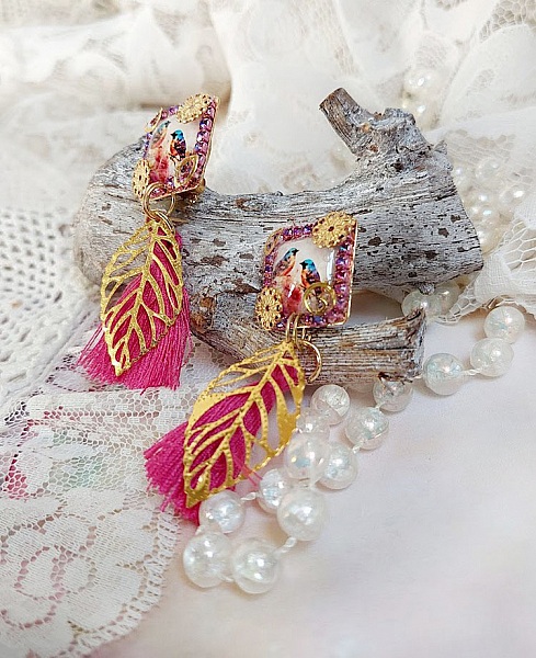Boucles d'oreilles carrées avec oiseaux, pompons roses et feuilles dorées.
