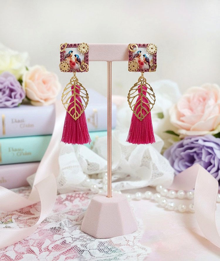 Boucles d'oreilles carrées avec oiseaux, breloques dorées et pompons fuchsia.