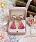 Boucles d'oreilles carrées avec oiseaux, pompons roses et breloques dorées.