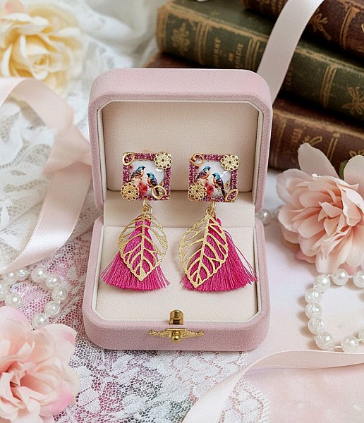 Boucles d'oreilles carrées avec oiseaux, pompons roses et breloques dorées.