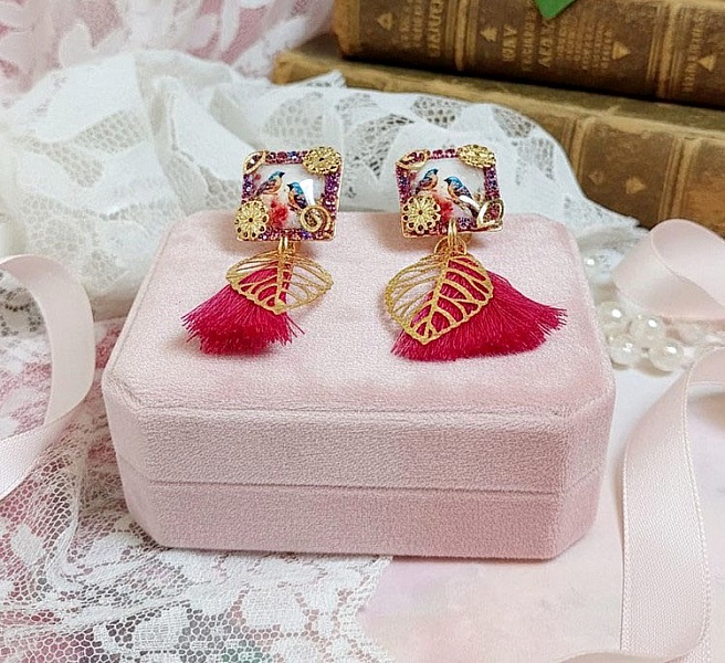 Boucles d'oreilles carrées avec oiseaux, pompons roses et breloques dorées.