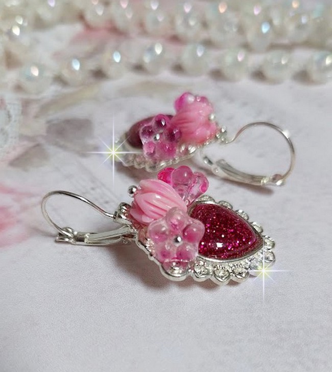 BO C&oelig;ur Ardent mont&eacute;es avec des dormeuses argent&eacute;es &agrave; laquelle s&rsquo;ajoute des c&oelig;urs paillet&eacute;s en r&eacute;sine Fuchsia. Ils sont orn&eacute;s d&rsquo;un bouquet de fleurs en verre &agrave; la couleur Rose pour un style romantique